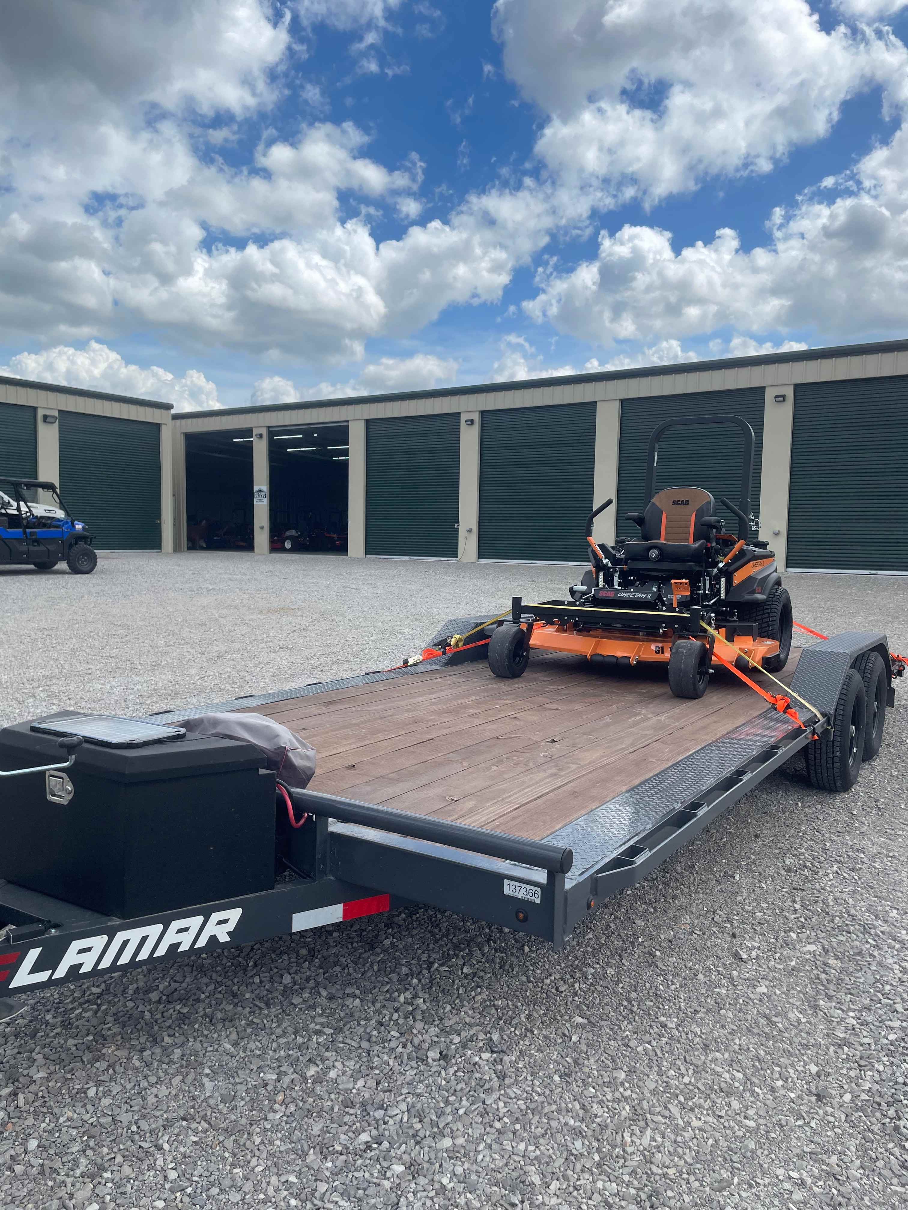Car hauler trailer loaded with a zero-turn mower for rental